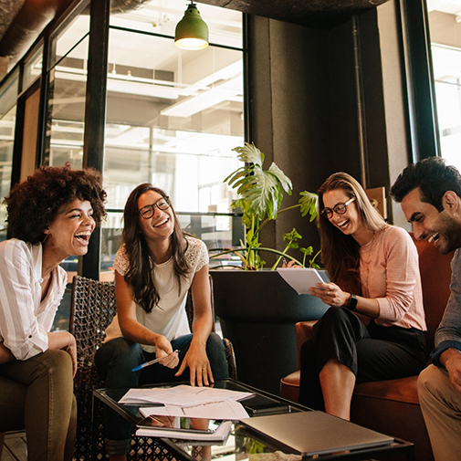Four adults laughing together while seated around a coffee table
