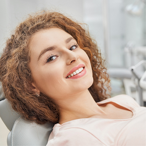 Smiling young woman leaning back in the dental chair