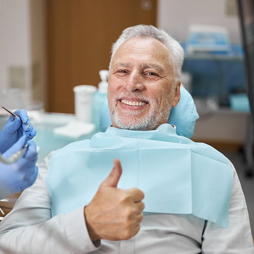 Senior dental patient smiling and giving a thumbs up
