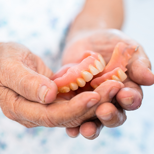 Senior holding a set of dentures