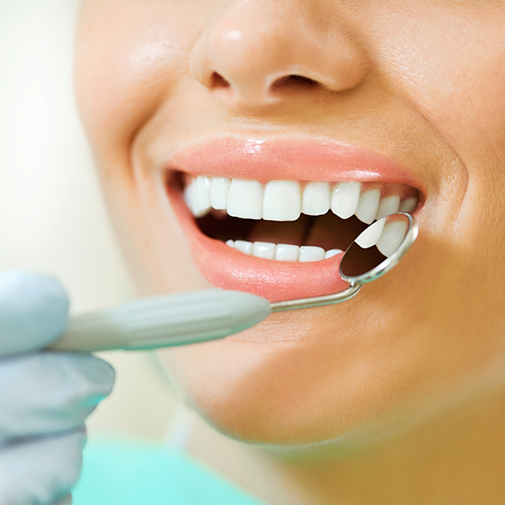 Close up of a smiling mouth being examined by a dentist