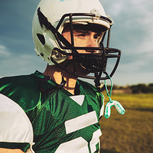 Football player with an athletic mouthguard attached to their helmet
