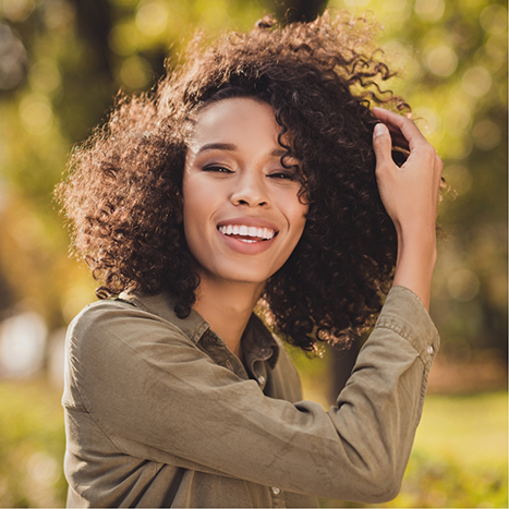 Woman smiling in the sun after cosmetic dentistry in Rogers