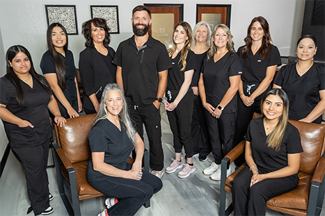 Two smiling Rogers dental team members with a young girl in the dental chair giving thumbs up